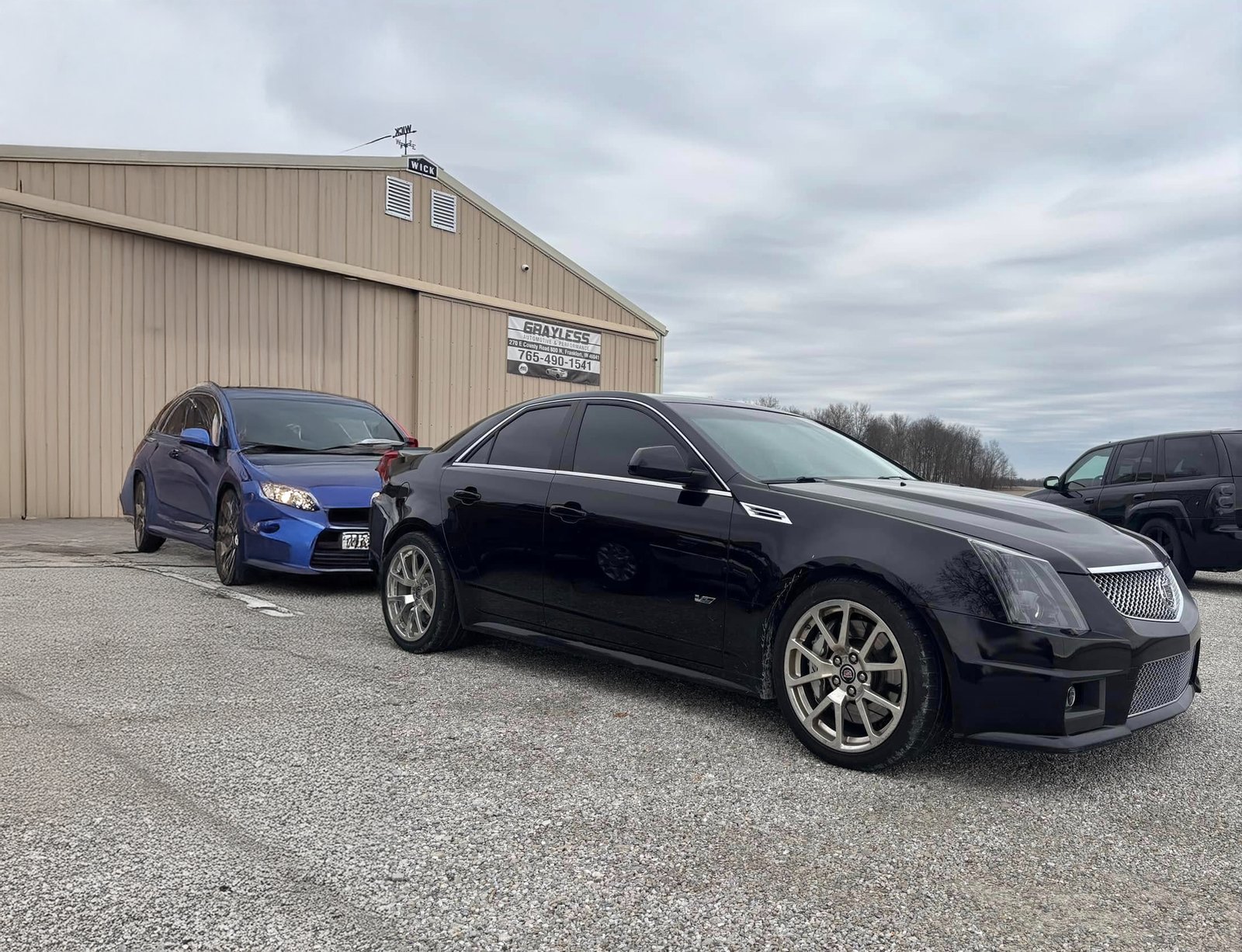 Exterior view of the Grayless Automotive facility in Clinton County, featuring the main entrance, customer parking, and shop signage.